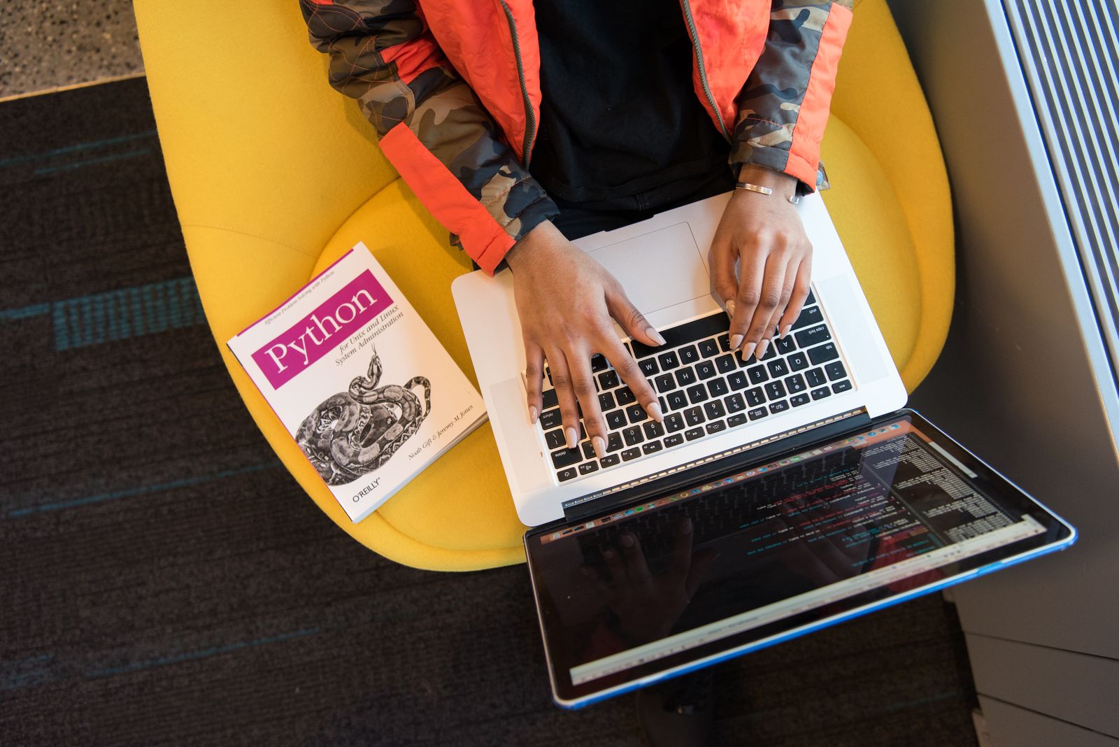 A developer working on a laptop with a programming reference book nearby